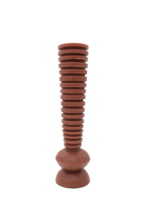 A reddish-brown decorative candle with a fluted cylindrical body and a rounded base, photographed against a plain white studio background.