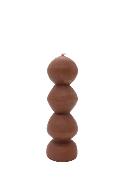A sculptural, multi-tiered pillar candle made of amber wax, featuring organic, rounded stacked shapes.