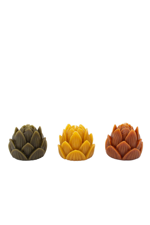 Three small lotus-shaped decorative candless in olive green, mustard yellow, and terracotta orange,